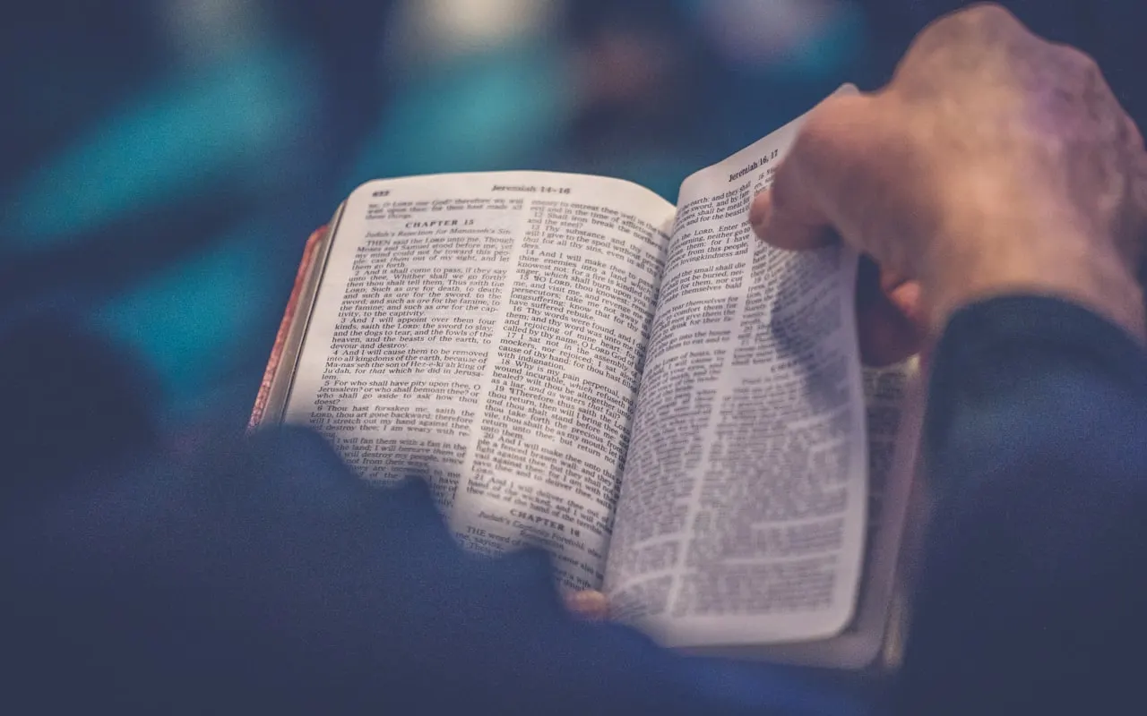An open Bible resting on a wooden table in soft morning light